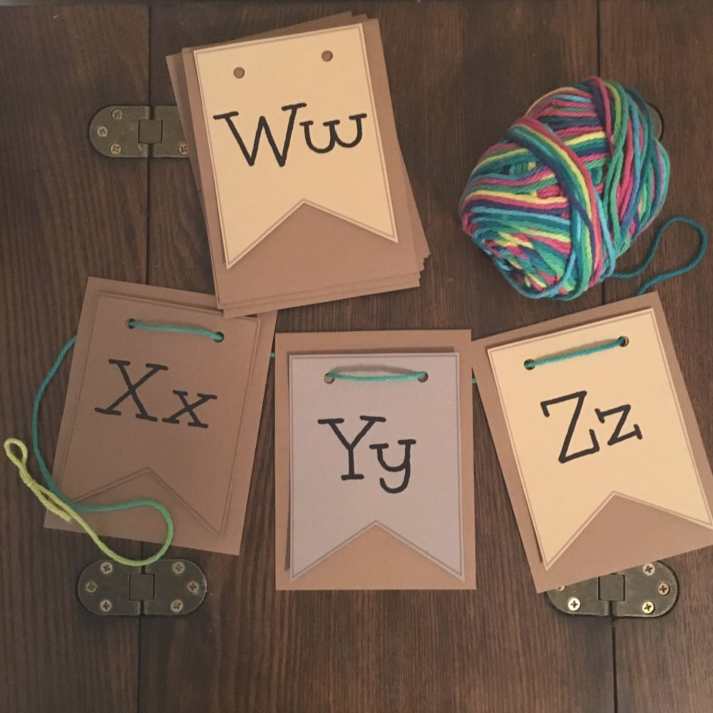 alphabet cards on wood table with yarn through holes on top