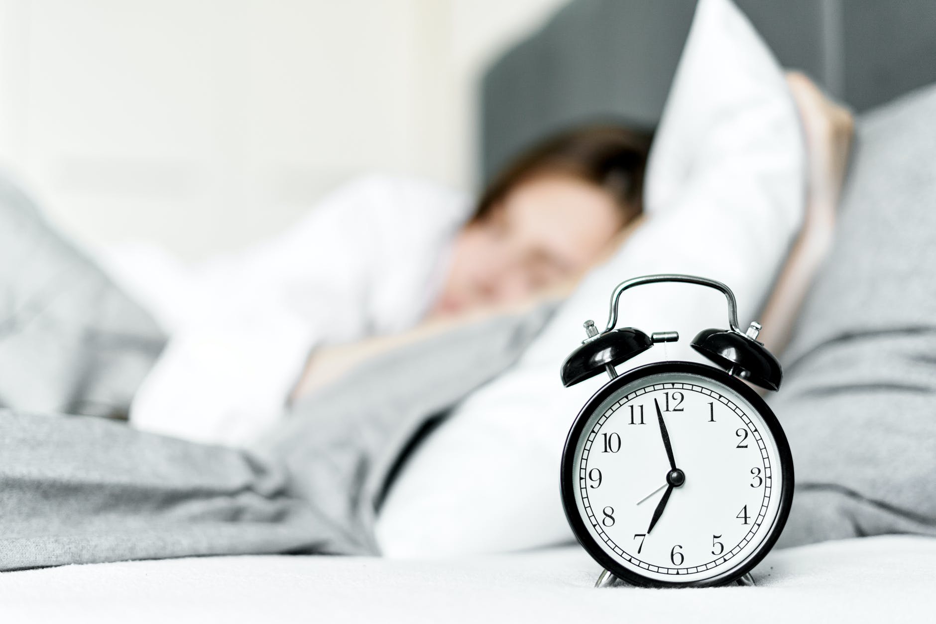 an alarm clock on bedside near a sleeping woman